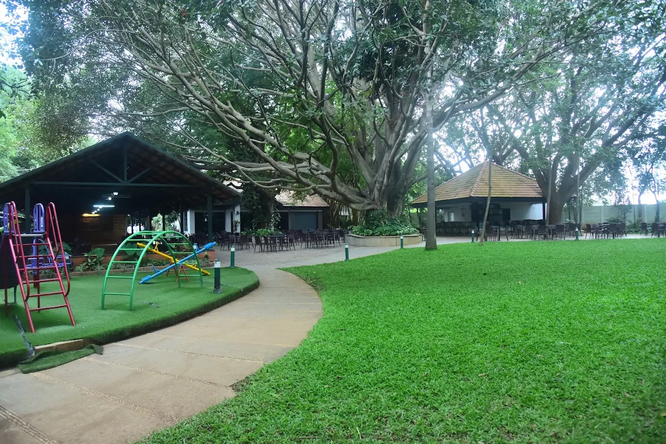 K. C. Palace Club clubhouse, garden lawn and children’s play area beneath a large tree